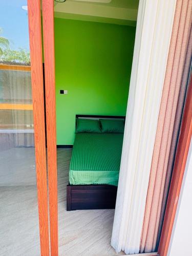 a bed in a room with a green wall at Galle srilanka in Balapitiya
