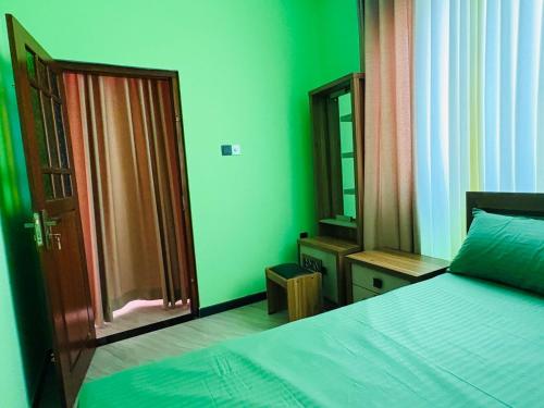 a bedroom with green walls and a bed and a mirror at Galle srilanka in Balapitiya