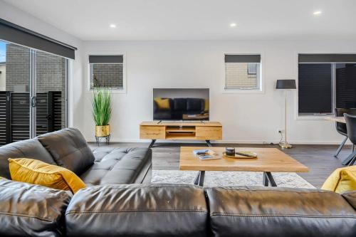 a living room with a leather couch and a table at Villa 4 NEW 3Bed 2 Bath in Warrane