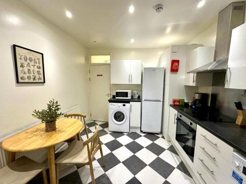 a kitchen with a table and a stove and refrigerator at Delux Rooms Near City Centre in London