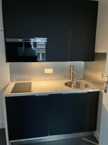 une cuisine avec un évier et un micro-ondes dans l'établissement Petit PARIS, à Paris