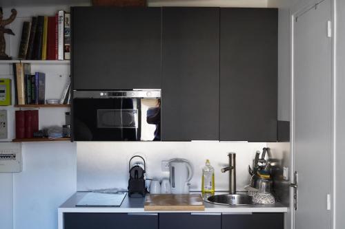 - une cuisine avec des placards noirs et un évier dans l'établissement Petit PARIS, à Paris