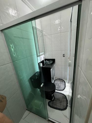Un baño con inodoro y una pared de cristal. en Apartamento 2 Quartos Próximo a Praia, en Rio das Ostras