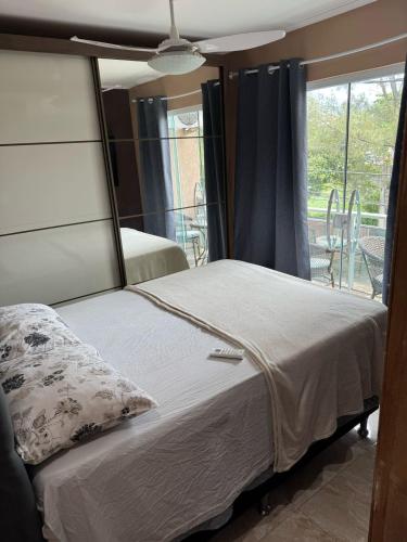 Un dormitorio con una cama grande con ventana. en Apartamento 2 Quartos Próximo a Praia, en Rio das Ostras