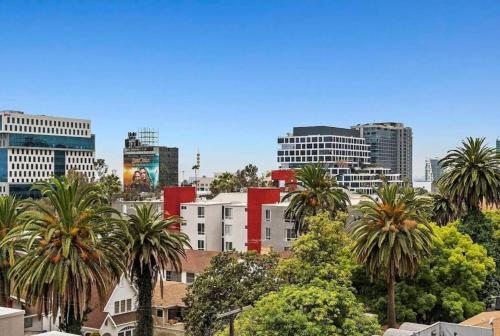 a city skyline with palm trees and buildings at Snazzy 2Bd Apartment Rooftop Pool & Iconic Hollywood Sign Views in Los Angeles