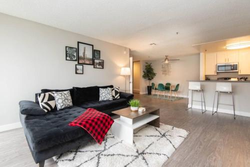 a living room with a black couch and a kitchen at Snazzy 2Bd Apartment Rooftop Pool & Iconic Hollywood Sign Views in Los Angeles