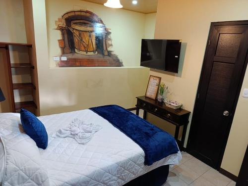 a bedroom with a bed and a flat screen tv at Hotel El Tambor OASIS Antigua Guatemala in Antigua Guatemala
