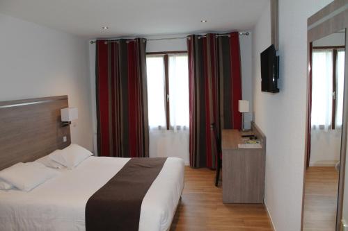 a hotel room with a bed and a television at Logis Hotel Restaurant de l'Abbaye in Ferrières