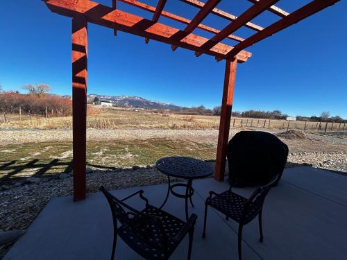 a table and two chairs on a porch with a view of a field at Posh Cottage Wine Country Mountain View Retreat in Palisade