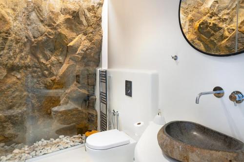a bathroom with a sink and a rock wall at Ria Mar Villas & Suites by Live&Travel in Houlakia