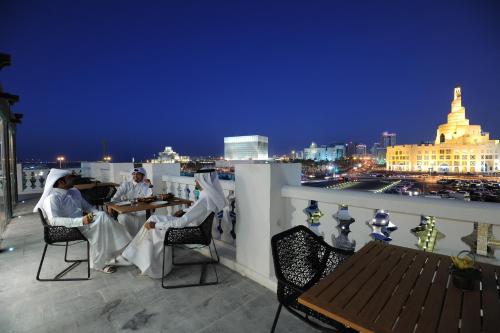 two people sitting at tables on a balcony at night at Souq Waqif Boutique Hotels - Tivoli in Doha