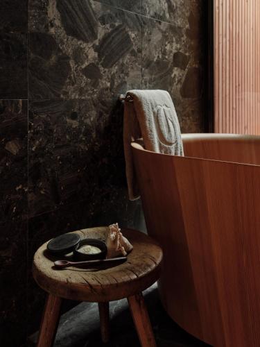 a bathroom with a wooden stool next to a bath tub at Chiemgauhof Lakeside Retreat in Übersee