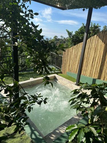 a swimming pool in a yard with a wooden fence at Tahiti Casa Campestre in Santa Bárbara