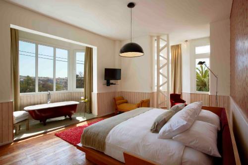 1 dormitorio con 1 cama grande, bañera y ventana en Palacio Astoreca, en Valparaíso