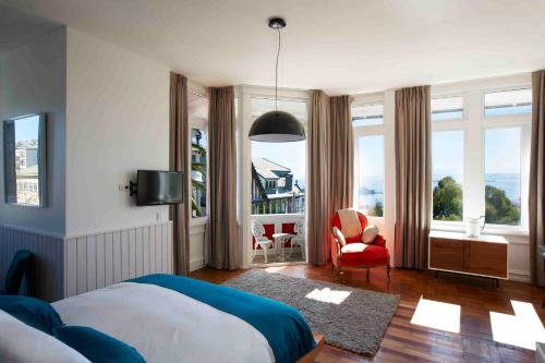 1 dormitorio con 1 cama, 1 silla y ventanas en Palacio Astoreca, en Valparaíso