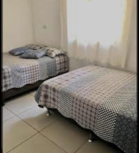 two twin beds in a room with a window at Viver de Temporada Canindé- 15 Minutos de Piranhas in Canindé de São Francisco