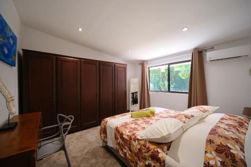 a bedroom with a bed and a desk and a window at Villa Te Torea in Arue