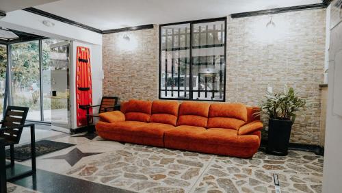 an orange couch in a room with a brick wall at Hotel Balcones del Estadio in Medellín