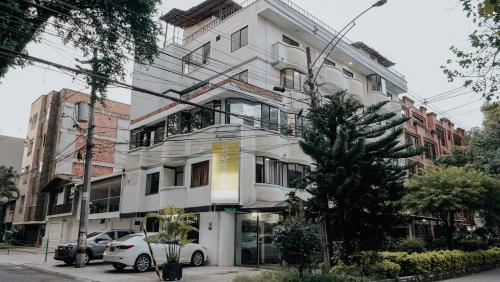 a white building with a car parked in front of it at Hotel Balcones del Estadio in Medellín