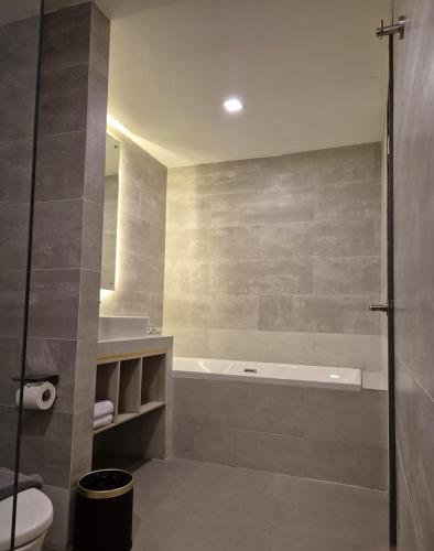 a bathroom with a tub and a toilet and a sink at LYNN Hotel Tuban in Tuban