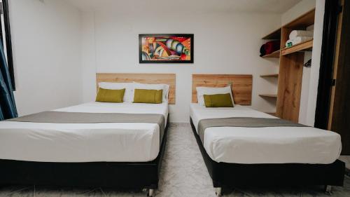 two beds sitting next to each other in a room at Hotel Balcones del Estadio in Medellín