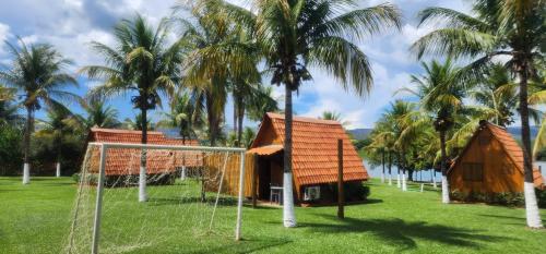 a resort with palm trees and a net at Pousada Lago Azul in Delfinópolis