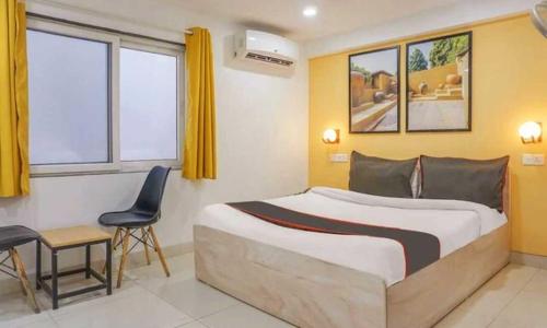 a bedroom with a bed and a desk and a chair at Hotel O Galaxy Hospitality in Pune