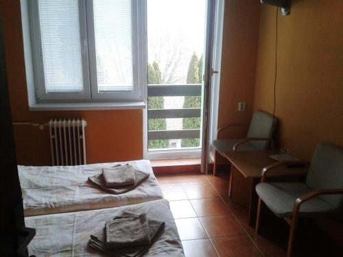 Habitación con cama, 2 sillas y ventana en Garni Hotel Sonata en Trenčianske Teplice