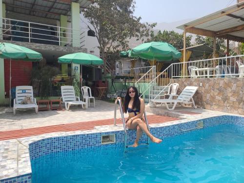 a woman in a bikini sitting in a swimming pool at Hostal Sol de Chosica in Chosica