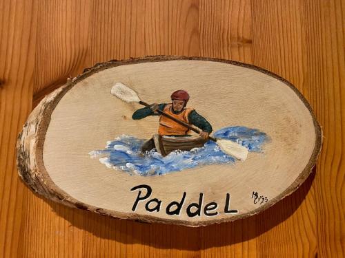 a wooden plaque with a picture of a man in a canoe at Schumacher's Landhaus - Bücherhotel in Friedeburg