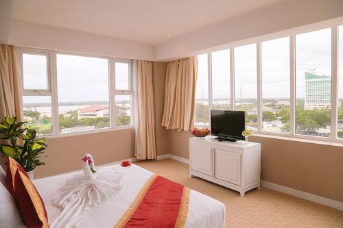 a bedroom with a bed and a tv and windows at NINH KIỀU FORTUNELAND HoTel in Can Tho