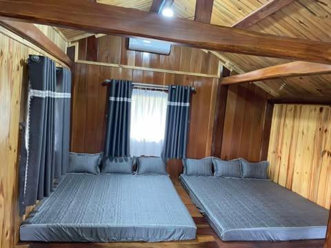 une chambre avec deux lits dans une cabane en bois dans l'établissement Pơ Lang Farmstay, à Bien Ho