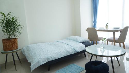 a bedroom with a bed and a table and chairs at Blue Belle Staycation Pollux Habibie in Batam Center