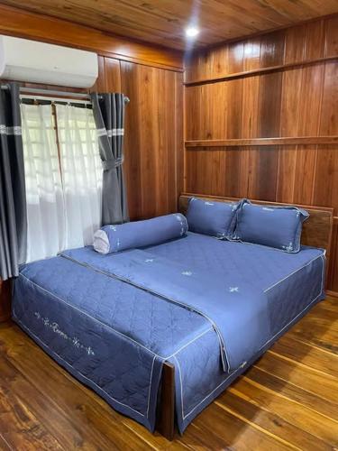 un lit bleu dans une chambre aux murs en bois dans l'établissement Pơ Lang Farmstay, à Bien Ho