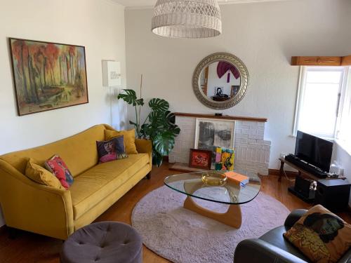 a living room with a yellow couch and a glass table at Riverside City Villa with Hot tub in Nelson