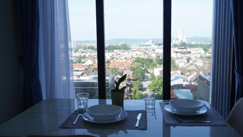 a dining table with a view of a city from a window at Blue Belle Staycation Pollux Habibie in Batam Center