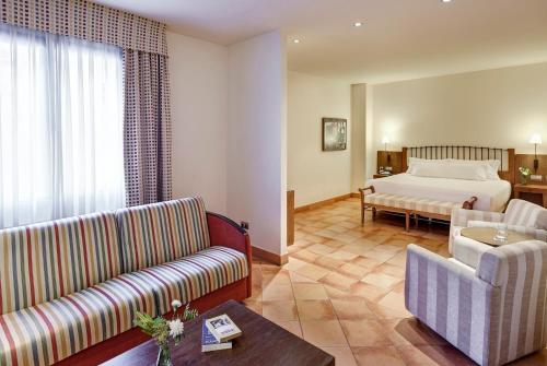 a hotel room with a bed and a living room at Sercotel Toledo Renacimiento in Toledo