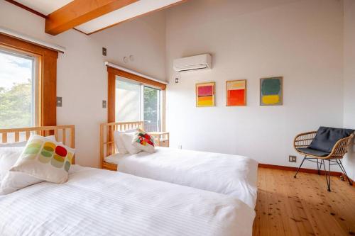 a bedroom with two beds and a chair and a window at プライベート天然温泉 - 広々清潔 - 素敵な非日常! Private Hot Spring - Spotless Modern Japanese in Ito