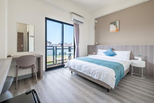 a bedroom with a bed and a desk and a window at Penghu Lemongrass in Magong