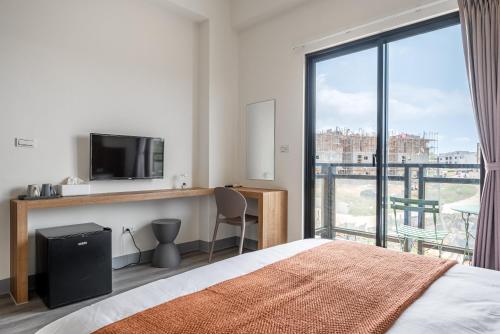 a bedroom with a bed and a desk with a television at Penghu Lemongrass in Magong