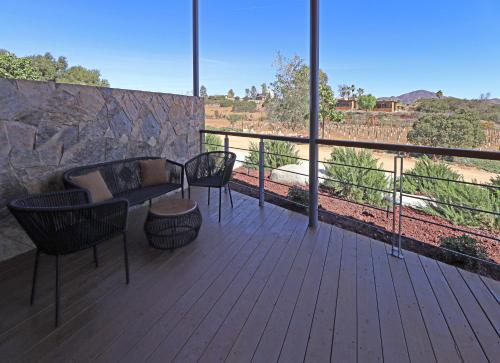 a balcony with chairs and a couch and a view at Parra del Valle Hotel Boutique in Valle de Guadalupe