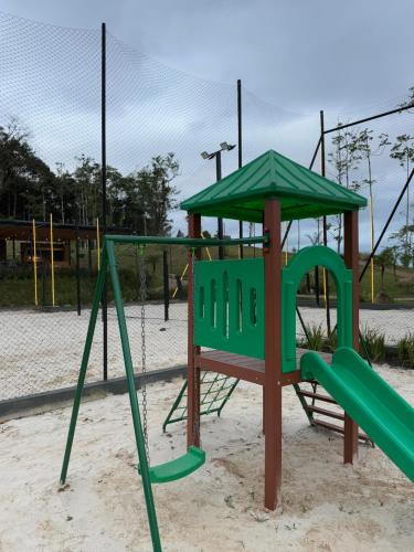 a playground with a green swing set in the sand at Camping do Bosque - Deck 01 in Rodeio