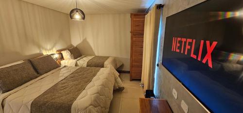 a hotel room with two beds and a television at Pousada Alpes Azul in Campos do Jordão