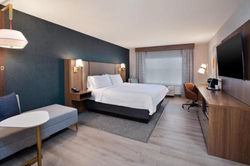 a hotel room with a bed and a desk and a tv at Holiday Inn Ontario Airport - California by IHG in Ontario