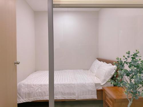a bedroom with a bed with white sheets and a plant at The Sóng Vũng Tàu Escape Apartment in Vung Tau