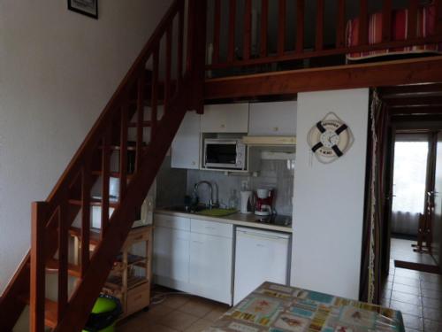 une cuisine avec un escalier menant à un loft dans l'établissement Maisonnette à Barbâtre, 30m de la plage pour 4 pers - FR-1-823-57, à Barbâtre