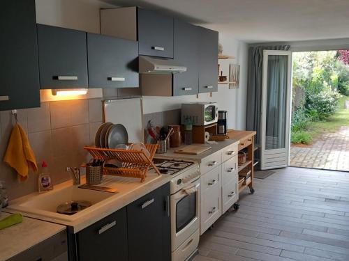 une cuisine avec des armoires blanches et un four à plaques de cuisson dans l'établissement Charmante maison proche plage, jardin, parking - FR-1-823-135, à Noirmoutier-en-l'lle