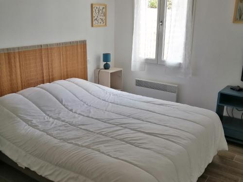 un grand lit blanc dans une chambre avec une fenêtre dans l'établissement Charmante maison proche plage, jardin, parking - FR-1-823-135, à Noirmoutier-en-l'lle