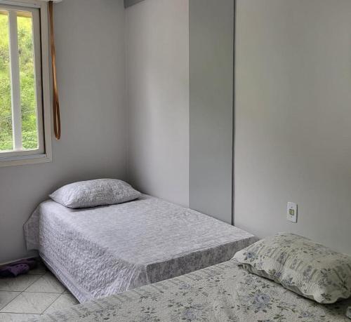 阿瓜斯迪林多亚Aconchegante Flat Cavalinho Branco Águas de Lindóia的有两张床和一扇窗户的卧室