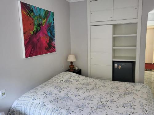 阿瓜斯迪林多亚Aconchegante Flat Cavalinho Branco Águas de Lindóia的卧室里有一张床，墙上挂着一幅画